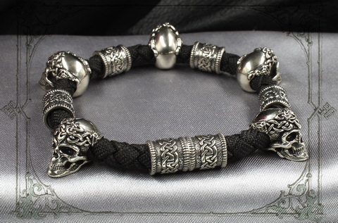 плетеный браслет с серебряными черепами и кельтским шармами