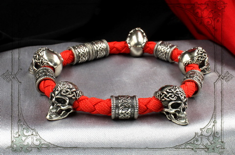 красный браслет с серебряными черепами и кельтскими шармами
